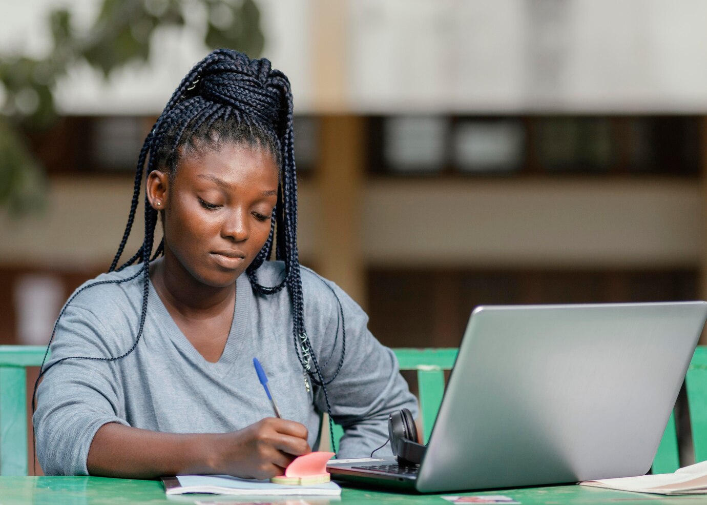 Happy black student using laptop while learning with her friends in a cafe,